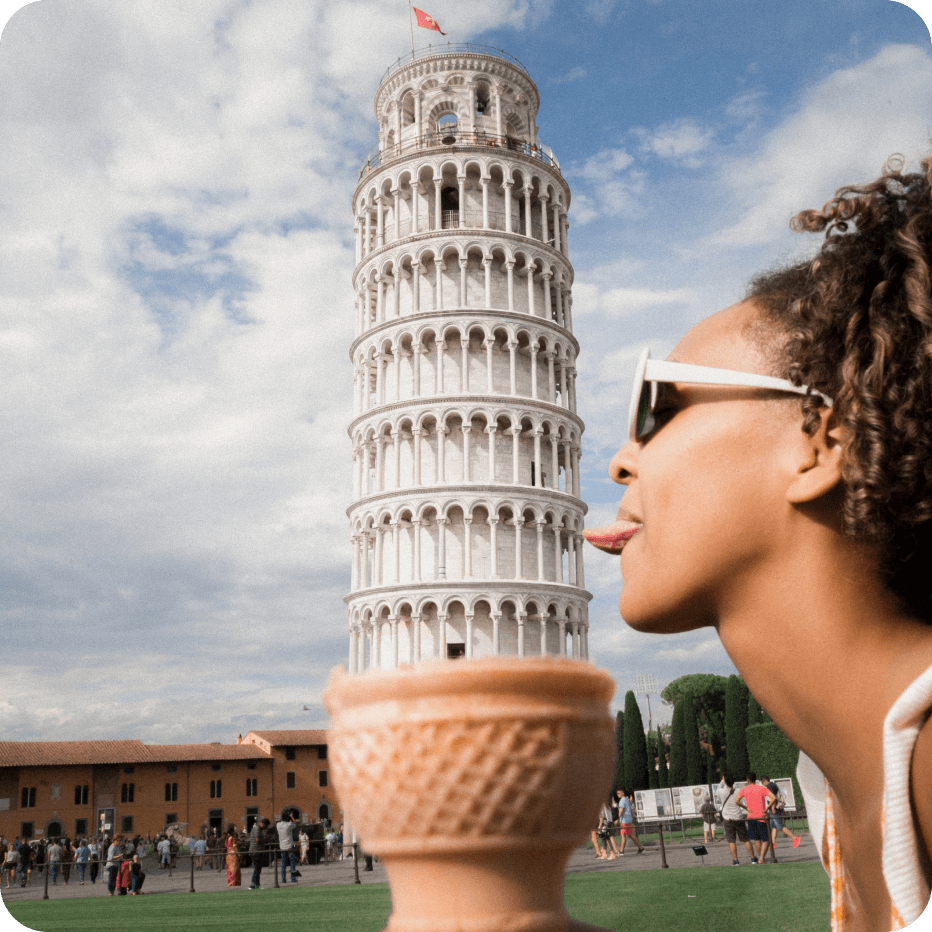 A woman poses with the Leaning Tower of Pisa. The tower appears to emerge from an ice cream cone; the woman extends her tongue to lick the tower.