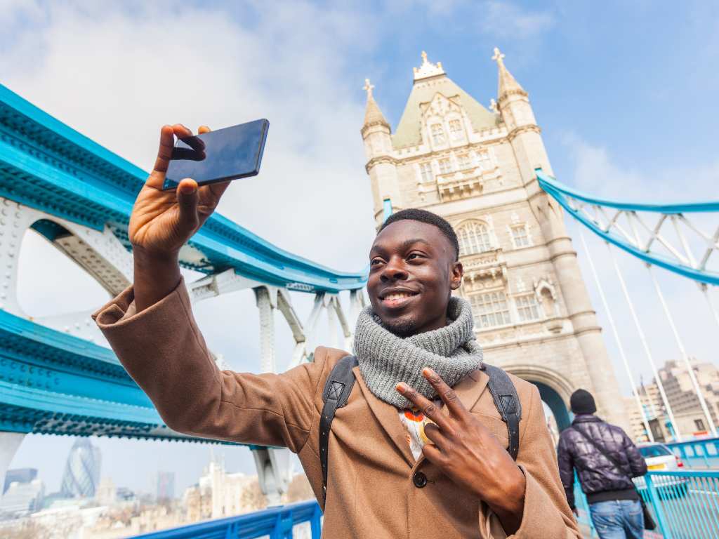 smiling man taking selfie in front of London Bridge.