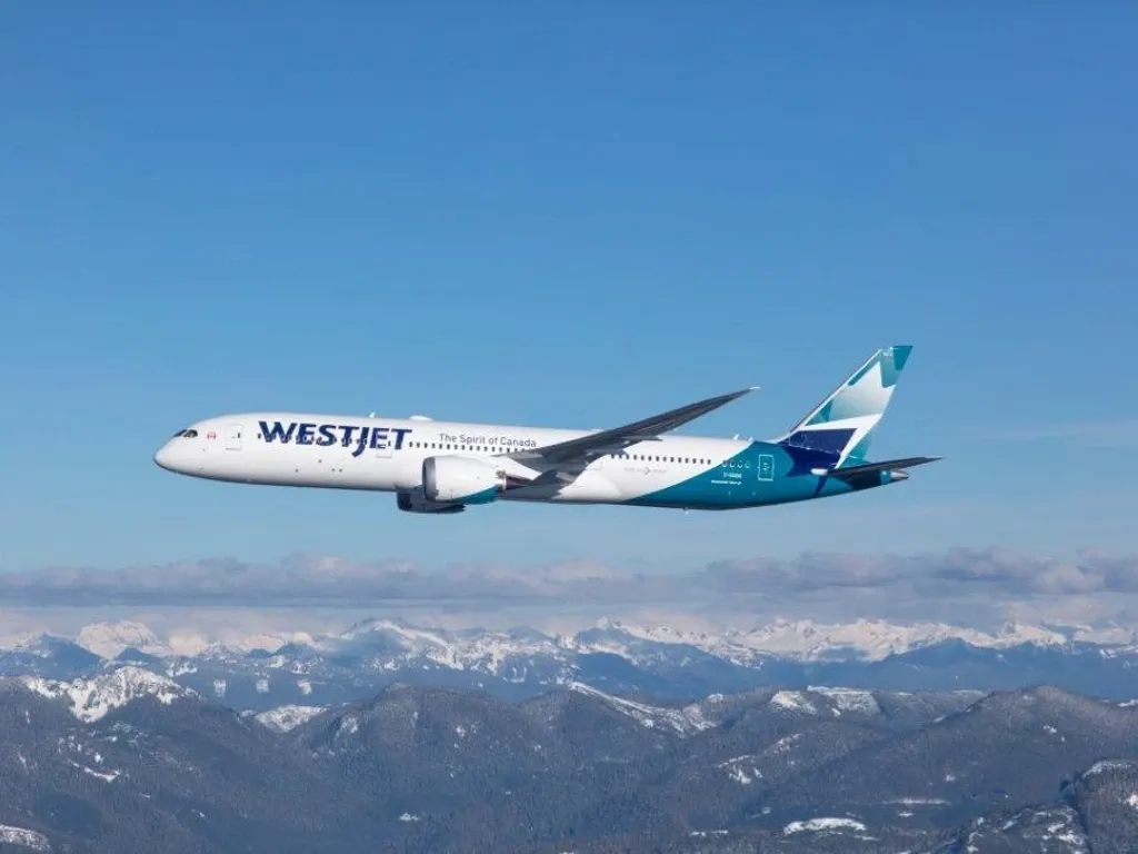 A WestJet airplane flies above the clouds