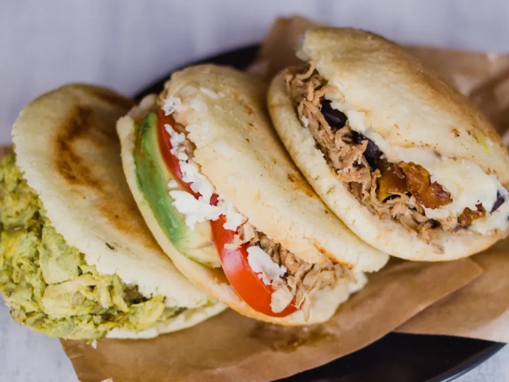 Arepas, stuffed with cheese, meats, and veggies sit on a board