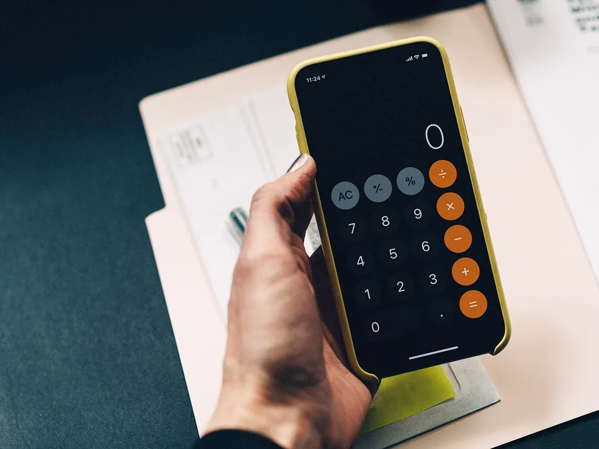 a hand holding a cellphone open to the calculator app