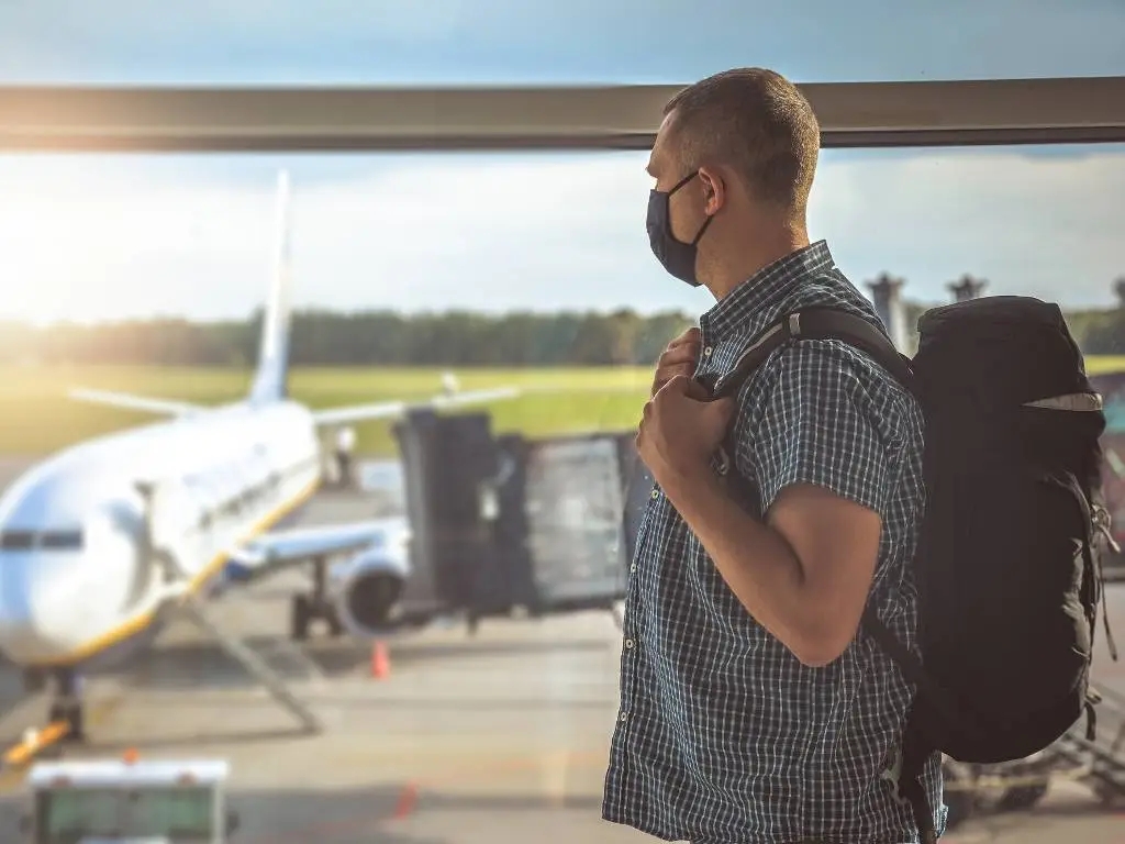 man getting ready to board his plane wearing a backpack. 