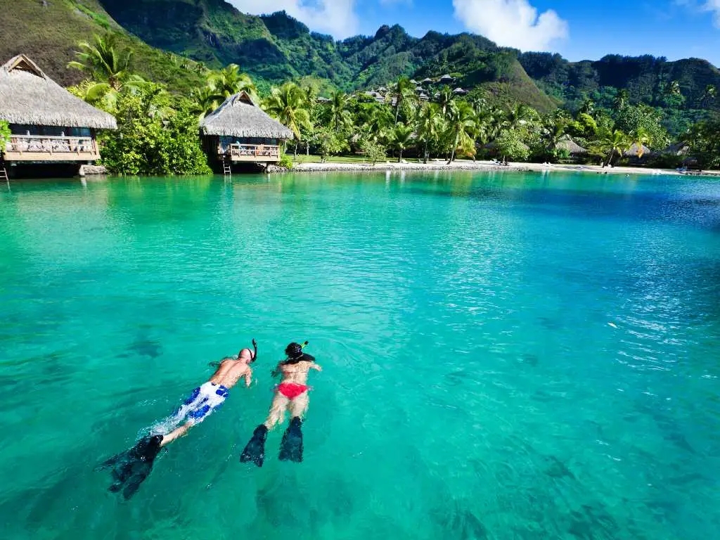 Young couple snorkeling in clean water over coral reef.
