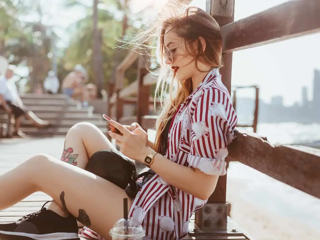 woman sitting down and looking at her smartphone.