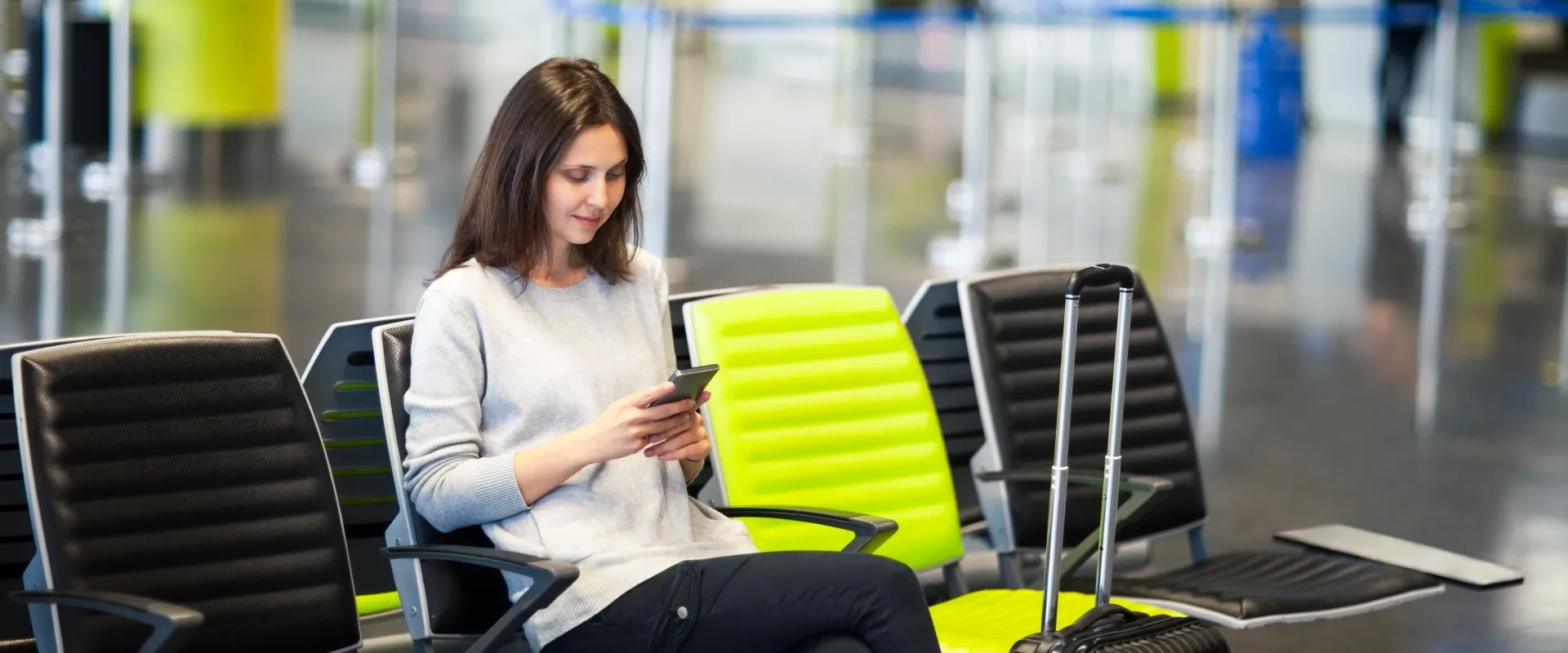 A woman looks at her phone at the airport