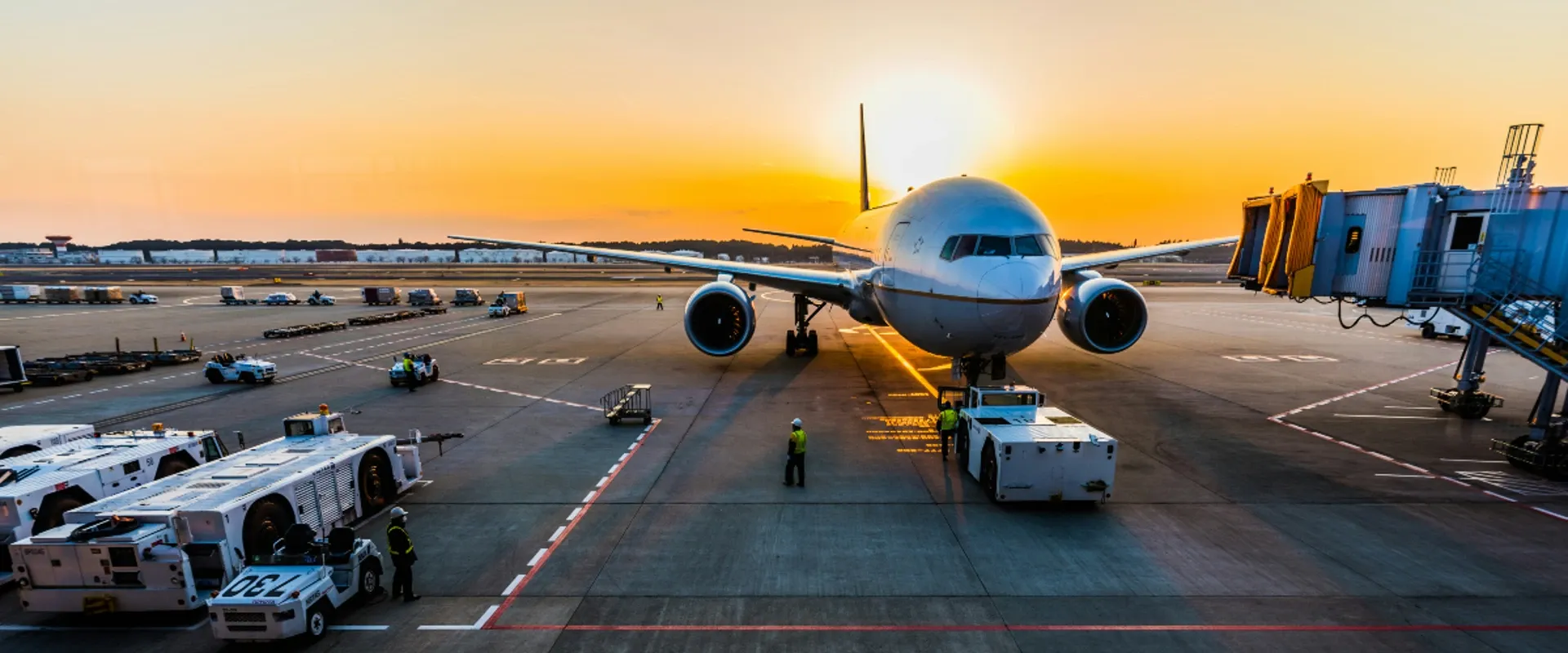 A plane sits at the gate at sunrise
