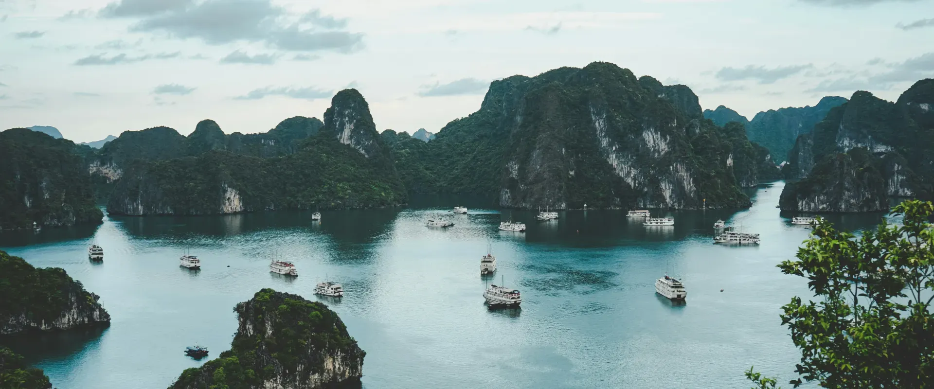Boats sit in blue water surrounded by mountainous islands in Vietnam