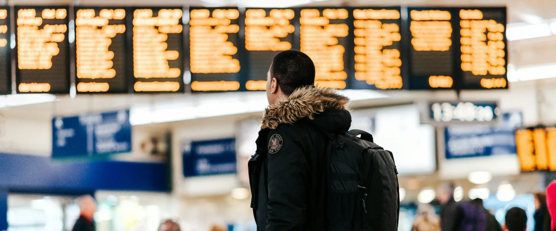 Man in a coat looks at the arrival and departures screens at the airport