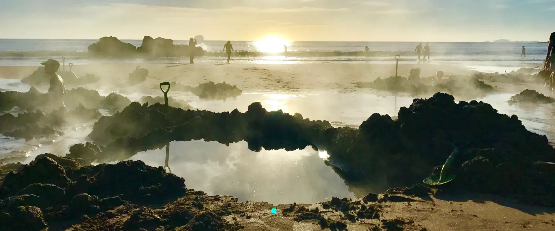 Steam rises from hot springs dug on Hot Water Beach in New Zealand