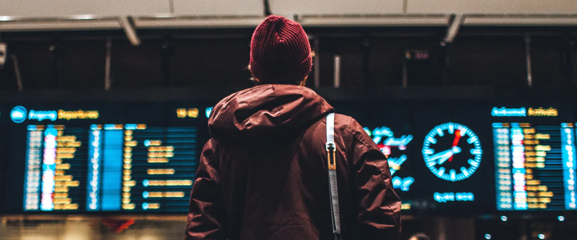 Passenger stands in front of departure board at airport