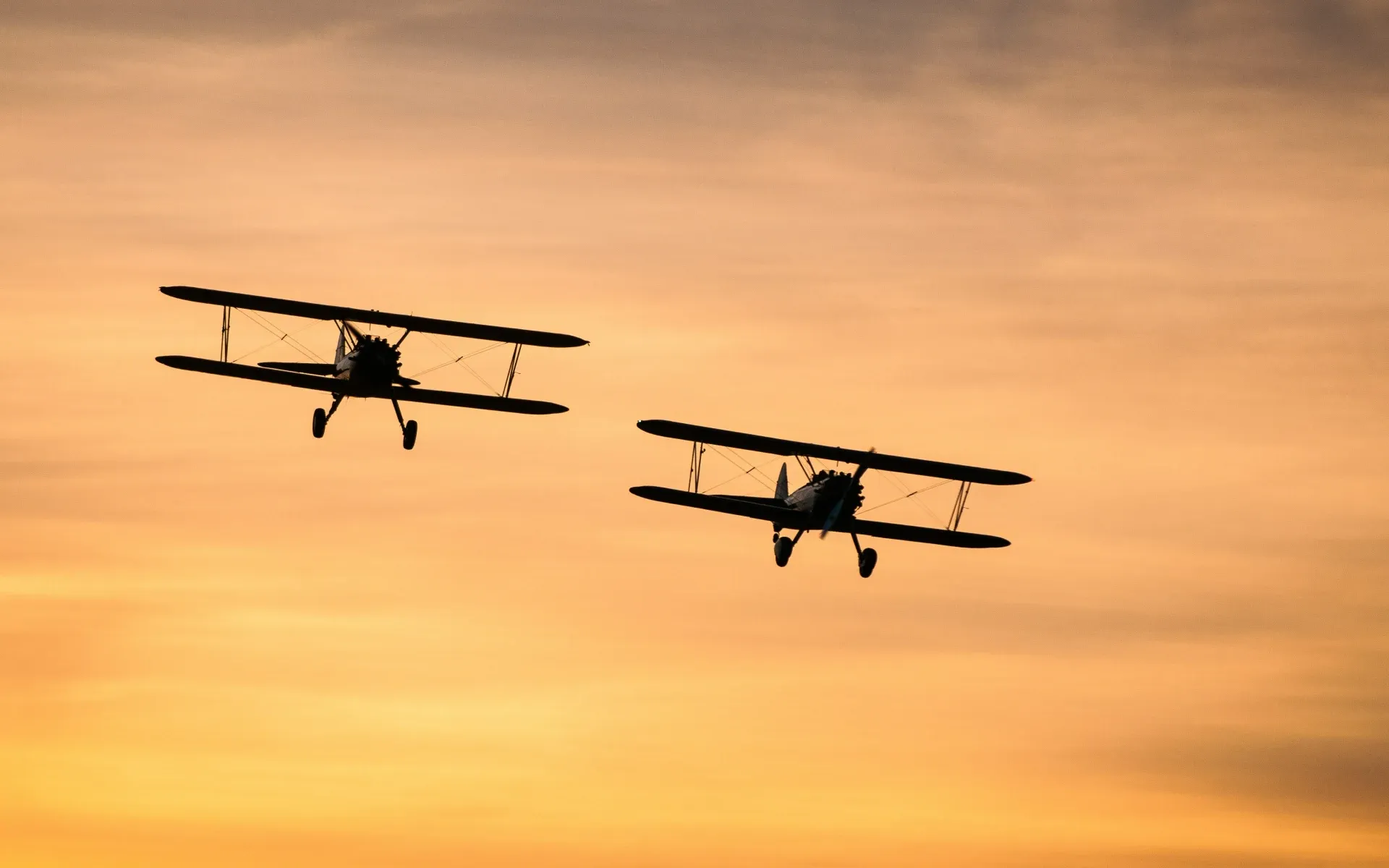 Two small planes flying at sunset