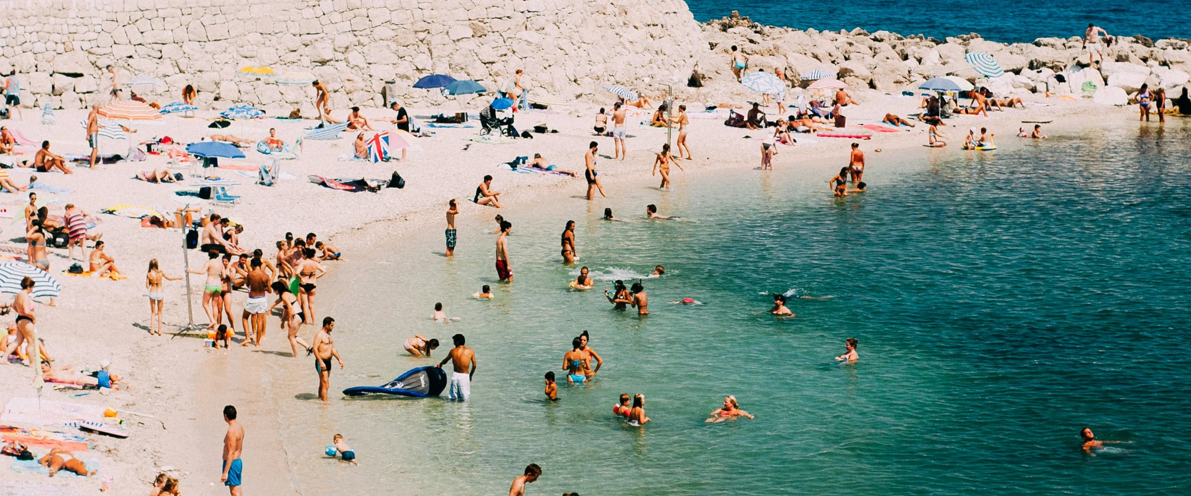 People stand on a beach and wade in the water